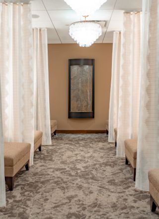 A serene lounge area with soft lighting, beige seating, sheer curtains, and a wall decoration framed in black.